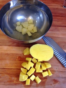 Cortando as batatas em cubinhos e jogando imediatamente na água fria